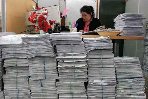 A health worker looking through a huge amount of stacked paper reports.